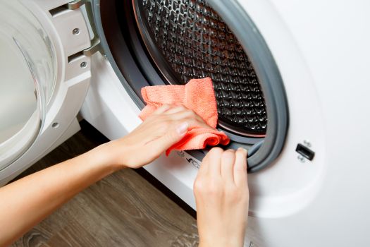Kobieta czyści pralkę szmatką