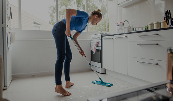 Dziewczyna sprząta kuchnię korzystając z mopa
